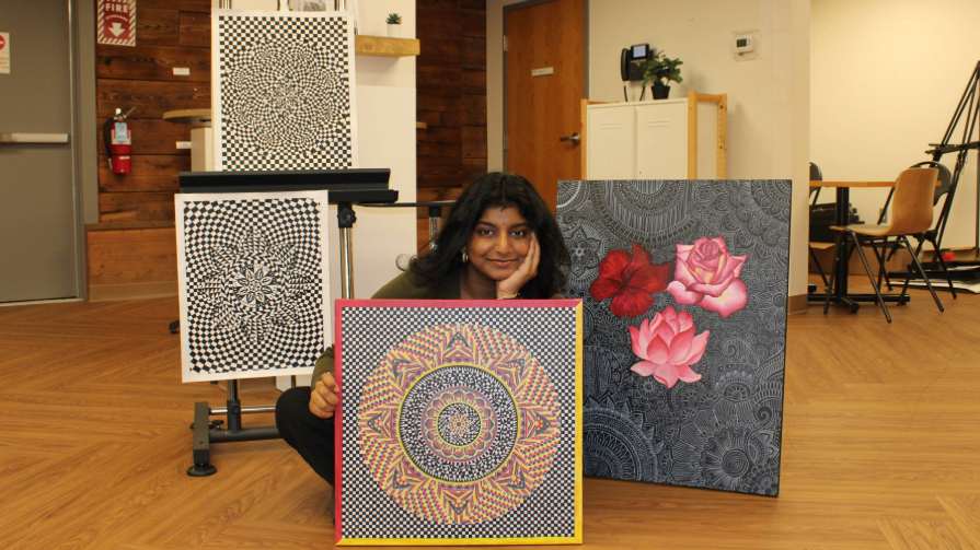 Bryant student poses with four mandalas.